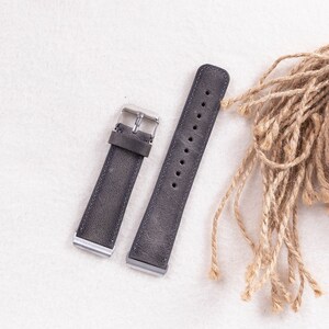 May include: Two gray leather watch straps with silver buckles. The straps are on a white surface.