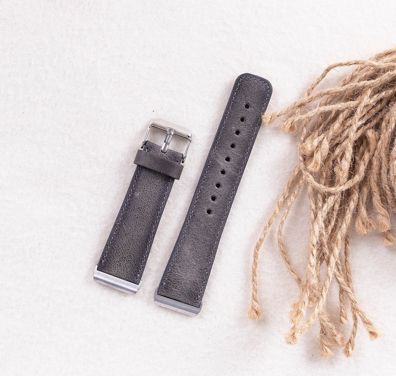 May include: Two gray leather watch straps with silver buckles. The straps are on a white surface.