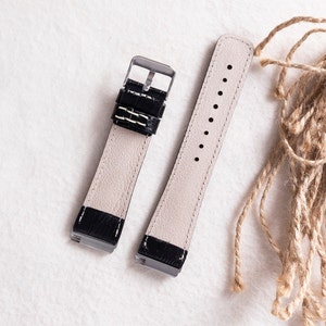 May include: Two black leather watch straps with silver buckles. The straps are laid out on a white surface.
