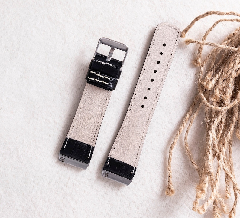 May include: Two black leather watch straps with silver buckles. The straps are laid out on a white surface.