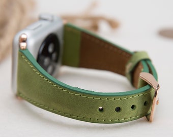 May include: A green leather watch band with rose gold hardware. The band is stitched with a contrasting green thread.