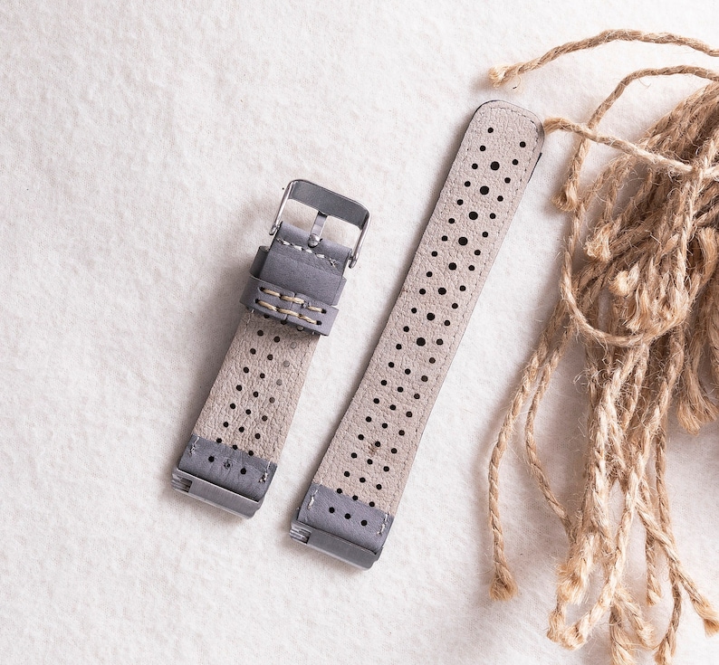 Puede incluir: Dos correas de reloj de cuero gris con un dise&ntilde;o perforado. Las correas tienen una hebilla plateada y costuras.