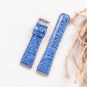 Puede incluir: Dos correas de reloj de cuero azul claro con un patr&oacute;n de cocodrilo. Las correas tienen hebillas plateadas.