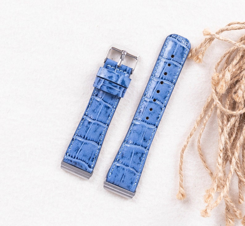 Puede incluir: Dos correas de reloj de cuero azul claro con un patr&oacute;n de cocodrilo. Las correas tienen hebillas plateadas.
