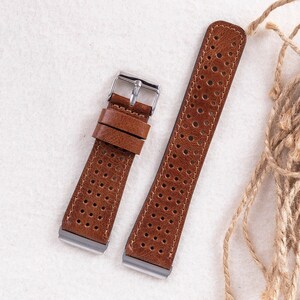 May include: Two brown leather watch straps with a perforated design. The straps have silver buckles.