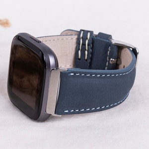 May include: A dark blue leather watch band with white stitching for a smartwatch. The band is made of soft, supple leather and has a classic look.