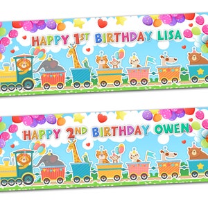 以下が含まれることがあります： 動物を乗せた列車が描かれたカラフルな横断幕2枚。1枚目は「Happy 1st Birthday Lisa」、2枚目は「Happy 2nd Birthday Owen」と書いてあります。