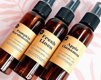Könnte beinhalten: Drei 60 ml braune Glasflaschen mit schwarzen Sprühköpfen und Etiketten. Die Etiketten sind braun mit goldenen Akzenten und zeigen die Namen der Düfte: Pumpkin Marshmallow, Fresh Linen und Apple Cinnamon. Jedes Etikett enthält auch den Text "Daisy Garden Gifts - Etsy" und "Handmade in Ohio".