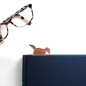 The bottom of the leather dog shaped bookmark peeks out from the top of the book, it can be used to the head emerges at the top of the book or the bottom