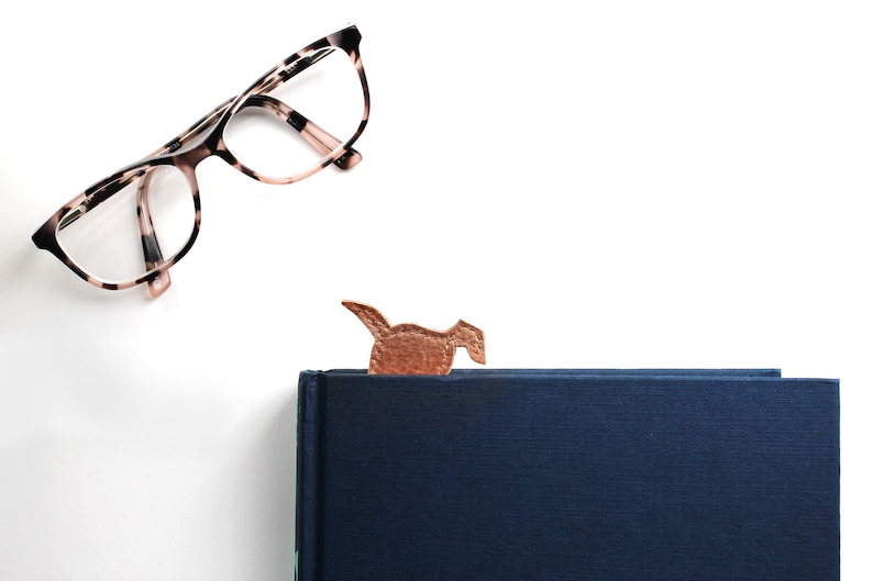 The bottom of the leather dog shaped bookmark peeks out from the top of the book, it can be used to the head emerges at the top of the book or the bottom