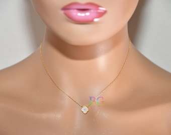 May include: A gold chain necklace with a small, four-leaf clover pendant set with clear cubic zirconia stones.