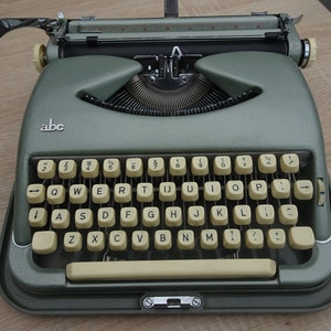 May include: A vintage green typewriter with a cream-coloured keyboard and the word "abc" printed on the front.