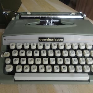 May include: A green vintage vendex s300 typewriter with a white keyboard and black keys.