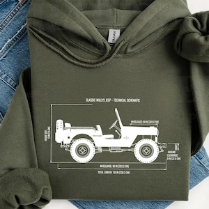 May include: An olive green hooded sweatshirt with a white schematic of a Classic Willys Jeep. The schematic includes measurements for wheelbase, ground clearance, and total length in inches and centimeters. The sweatshirt is folded over a pair of blue jeans.