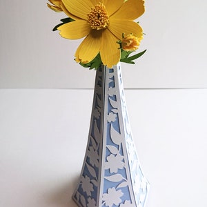 Puede incluir: Un ramo de flores de papel amarillo en un jarrón de cerámica azul y blanco.