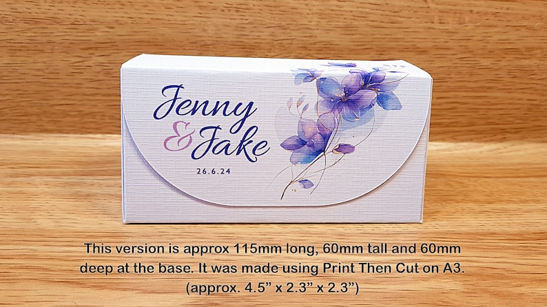 May include: A white box with a floral design and the text "Jenny & Jake 26.6.24". The box is approximately 4.5 inches long, 2.3 inches tall, and 2.3 inches deep.