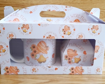 May include: A white gift box with a window showing two white mugs with a floral design and the text "If Mums Were Flowers I'd Pick You". The box has a handle and is decorated with a repeating pattern of the same floral design and text.