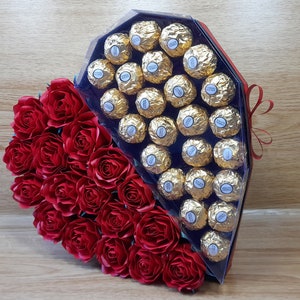 May include: A large heart-shaped box made of PVC, decorated with red paper roses, holds chocolates. The box is 11.02 inches wide, 11.02 inches tall, and 2.55 inches deep. The box is trimmed with a ribbon and bow. SVG file bundle includes the rose.