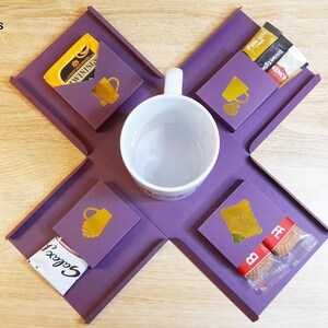 May include: Purple tray with four compartments for holding a mug, tea bags, coffee packets, and biscuits. The tray is made of a flexible material and folds flat for storage. The text "WININGS" and "Gocci" are visible on the packaging.