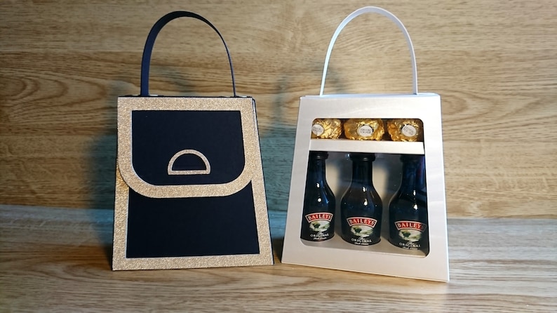 Pode incluir: Duas sacolas de presente, uma preta com acabamento de glitter dourado e outra branca com uma janela transparente. A sacola branca cont&eacute;m tr&ecirc;s garrafas em miniatura de Baileys Irish Cream e tr&ecirc;s trufas de chocolate douradas.