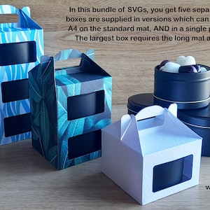 May include: Five different box designs for 8 oz tins. The boxes are made of cardboard and have a window to show the tin inside. The boxes are decorated with different patterns, including blue and white stripes, green leaves, and white. The tins are black and have a gold rim. The text on the image reads "These are 8oz tins which are 80mm wide and 53mm tall."