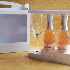 May include: A white gift box with a clear window, containing two small bottles of Freixenet Italian Rose sparkling wine and two champagne flutes.