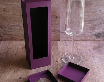 May include: A purple cardboard box with a window to display a wine glass. The box is open and the top flaps are folded back. Two smaller purple cardboard squares with cutouts are also included.