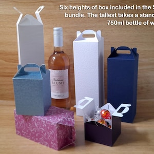 Könnte beinhalten: Sechs verschiedene Größen von Geschenkboxen mit einem Griff oben. Die höchste Box ist weiß und groß genug, um eine 750 ml Flasche Wein zu fassen. Die Boxen befinden sich auf einer Holzoberfläche.