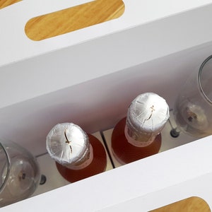 May include: A white gift box with a handle, containing two bottles of pink wine with silver foil tops and two clear glass wine glasses.