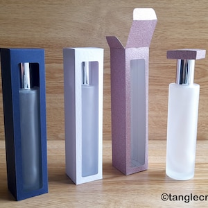 May include: Four perfume bottles in different coloured boxes. The boxes are blue, white, pink, and the fourth bottle is not in a box. The bottles are all clear glass with silver tops.