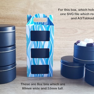 May include: A set of three black metal tins with a blue and white patterned box. The tins are 8 ounces each and measure 80mm wide and 53mm tall. The box has three cut-out windows to display the tins.  "For this box, which holds three tins, you get one SVG file which requires the long mat and A3/Tabloid card to cut. These are 8oz tins which are 80mm wide and 53mm tall."