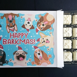 Könnte beinhalten: Ein blauer und weißer Adventskalender mit Hundemotiven. Der Kalender hat 24 Türen, jede mit einer anderen Hundeillustration. Der Text "HAPPY BARKMAS!" ist auf dem Kalender gedruckt. Der Kalender ist geöffnet und zeigt eine Schale mit weißen Schokoladen-Leckereien.