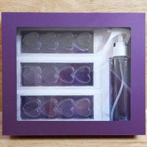 May include: A purple box with a clear window showing three rows of heart-shaped molds and a clear spray bottle. The box is 10 inches long, 8.5 inches wide, and 1.8 inches deep. The text on the box reads: "Finished size of box is approximately 250mm long x 215mm wide x 45mm deep. Please read listing description for mats and paper required."