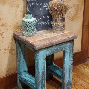May include: A rustic wooden side table with turquoise painted legs and a natural wood top. The table holds a decorative lantern, a tin can with dried grass, and a sign that reads "Life doesn't have to be perfect to be wonder."