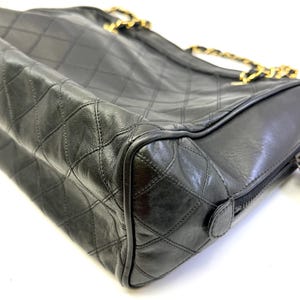 May include: Black quilted leather handbag with gold-tone chain straps. The bag features a diamond pattern and a zipper closure. The design is classic and elegant, suitable for various occasions.