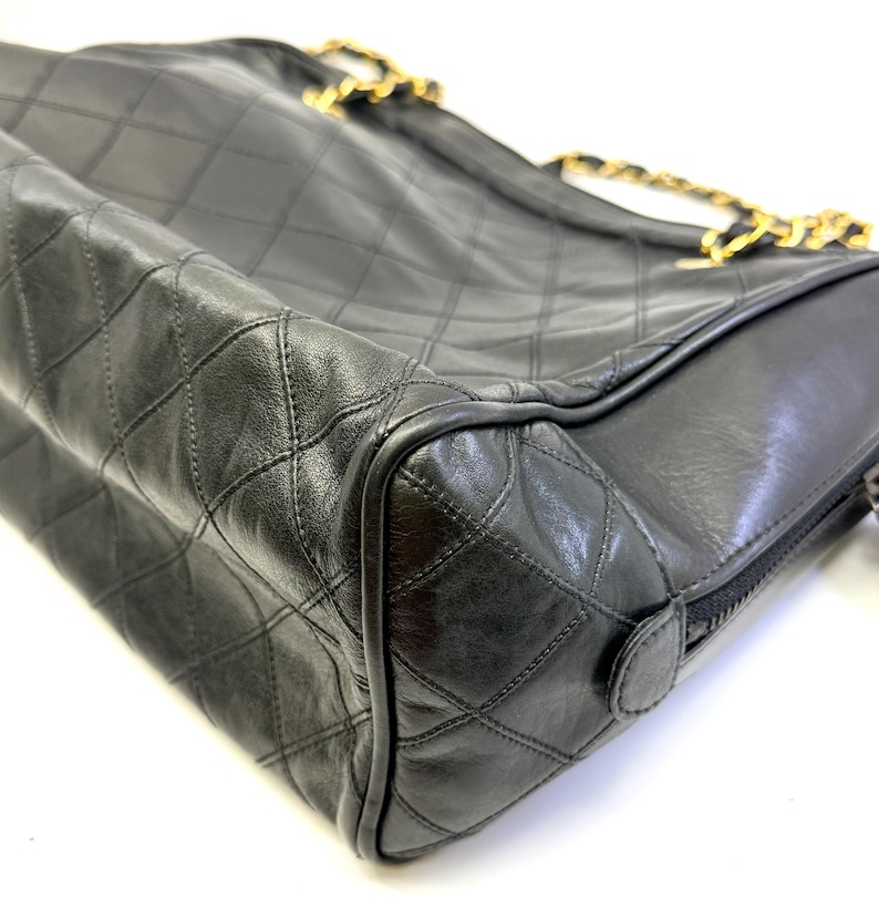 May include: Black quilted leather handbag with gold-tone chain straps. The bag features a diamond pattern and a zipper closure. The design is classic and elegant, suitable for various occasions.