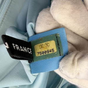 Puede incluir: Primer plano de una tela azul claro con una etiqueta negra que dice "FRANCE" y una etiqueta azul con el n&uacute;mero "7500945". Las etiquetas est&aacute;n adheridas a la tela.