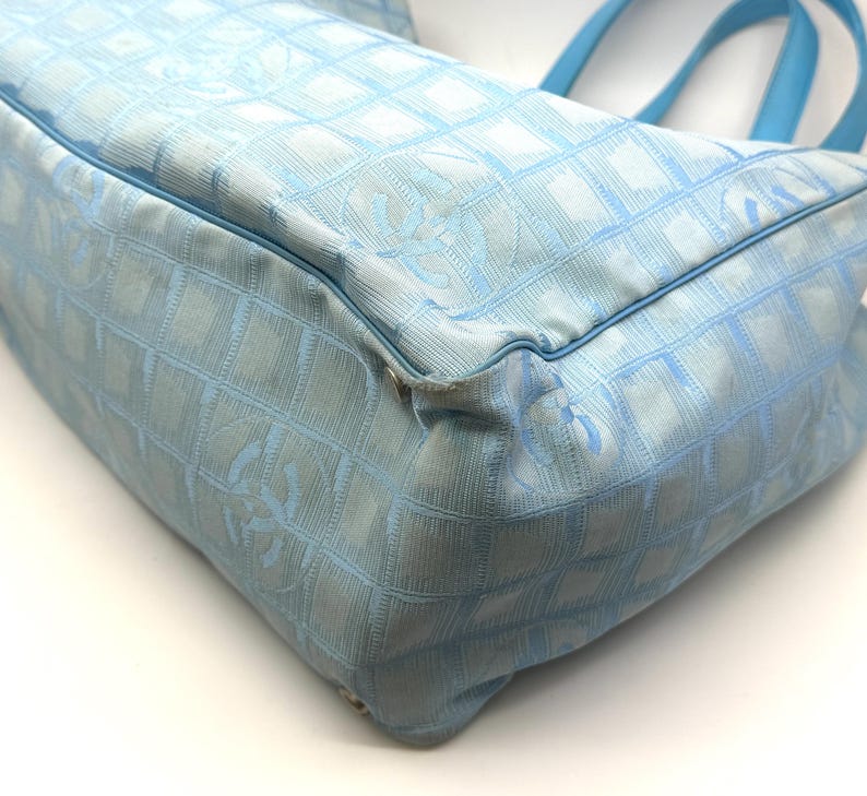 Puede incluir: Bolso tote azul claro con un patr&oacute;n acolchado y asas azules a juego. El bolso presenta un dise&ntilde;o de logotipo repetido. El bolso est&aacute; hecho de un material suave y texturizado.