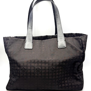 K&ouml;nnte beinhalten: Eine dunkelbraune Tragetasche mit sich wiederholendem Muster und silberfarbenen Griffen. Die Tasche hat eine rechteckige Form und ein strukturiertes Design. Die Griffe sind mit silberfarbenen Akzenten an der Tasche befestigt. Die Tasche besteht aus einem gewebten Material.