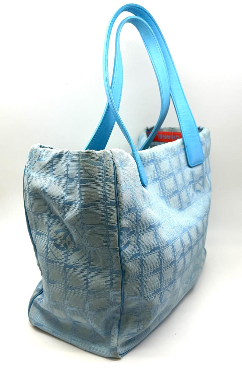 Puede incluir: Bolso tote azul claro con asas a juego. El bolso presenta un patr&oacute;n de cuadr&iacute;cula con logotipos repetidos. Las asas son de un tono azul m&aacute;s claro. El bolso est&aacute; hecho de un material suave.