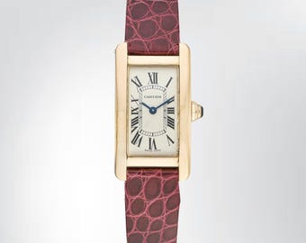 May include: A rectangular gold-tone wristwatch featuring a cream-colored dial with black Roman numeral hour markers, blue hands, and the Cartier logo. The watch is attached to a dark burgundy leather strap with a textured, embossed crocodile pattern.