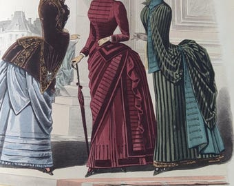 Może przedstawiać: Vintage ilustracja modowa zatytułowana Rachel’s Cottage Studio i Latest Paris Fashions, przedstawiająca trzy postacie w strojach z XIX wieku. Ubiory obejmują brązową marynarkę z jasnoniebieską spódnicą, ciemnoczerwoną suknię oraz zieloną suknię w paski.