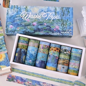 Könnte beinhalten: Ein weißes Box-Set mit Washi-Tape-Rollen mit verschiedenen künstlerischen Designs, darunter Seerosen und Landschaften. Der Deckel der Box trägt den Text "Washi Tape" und ein Seerosen-Gemälde. Das Set enthält 32 Rollen mit insgesamt 96 m Tape.
