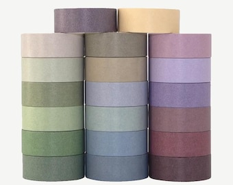 May include: Stacks of colorful washi tape rolls in shades of green, beige, blue, purple, and yellow. The rolls are arranged in three columns, with each roll appearing to be approximately 1 inch in diameter.