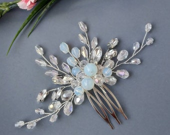 May include: A silver hair comb with a cluster of iridescent white and clear beads. The comb has a delicate, floral design.