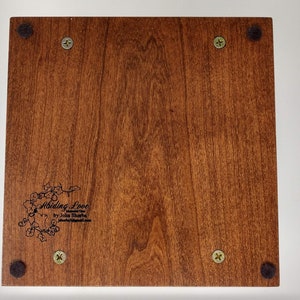 May include: A wooden box with a dark brown stain. The box has a black felt bottom and four black felt feet. The box has a black inscription that reads "Abiding Love by John Sharpe".
