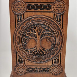 May include: A wooden box with a carved Celtic knot design and a tree of life motif. The box is made of dark wood and has a rich, brown finish.