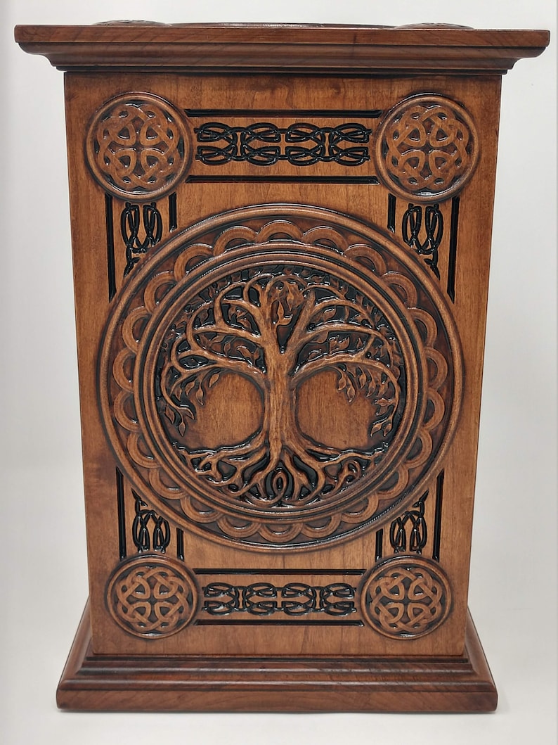 May include: A wooden box with a carved Celtic knot design and a tree of life motif. The box is made of dark wood and has a rich, brown finish.