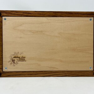 May include: A wooden box with a light wood interior and a dark wood frame. The box has a small engraved design on the inside that says "Abiding Love by John Shoba".