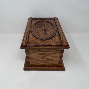 May include: A wooden box with a carved design on the lid. The box is made of oak wood and has a dark brown finish.